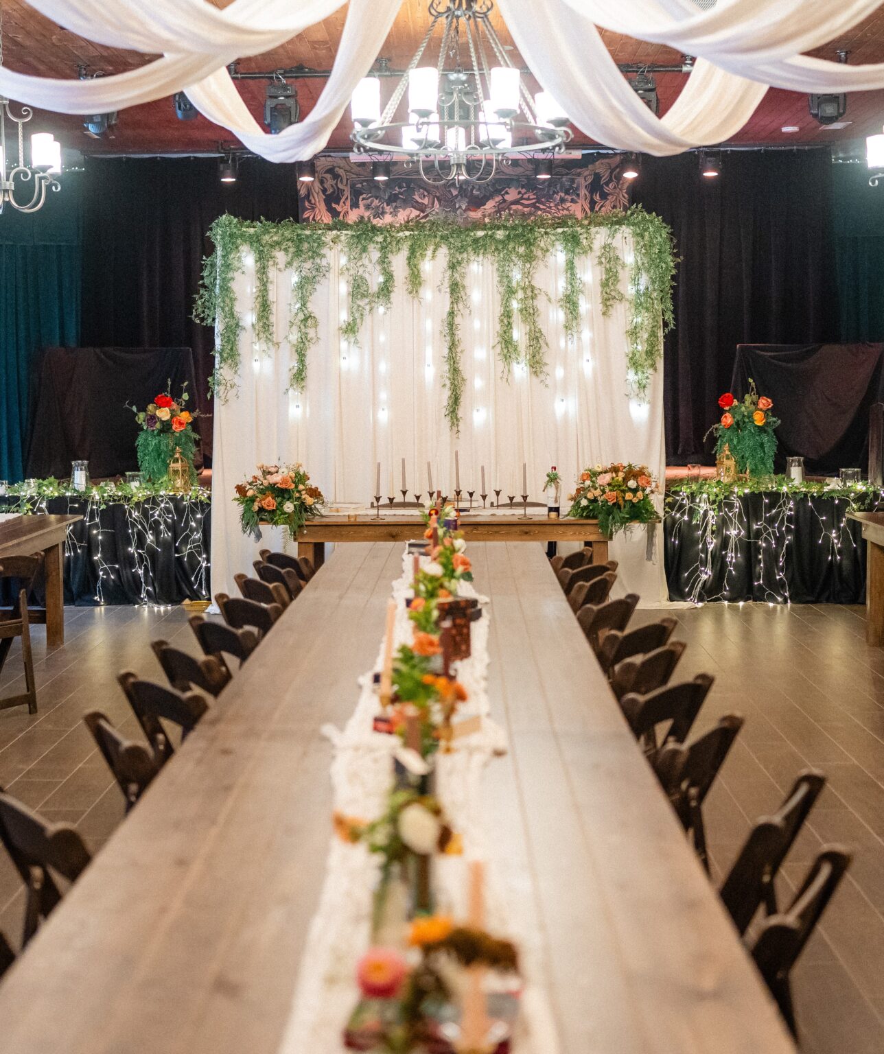 The Fae Nectar Great Hall decorated for a wedding with orange and red bouquets, greenery and a medieval fairy wedding vibe